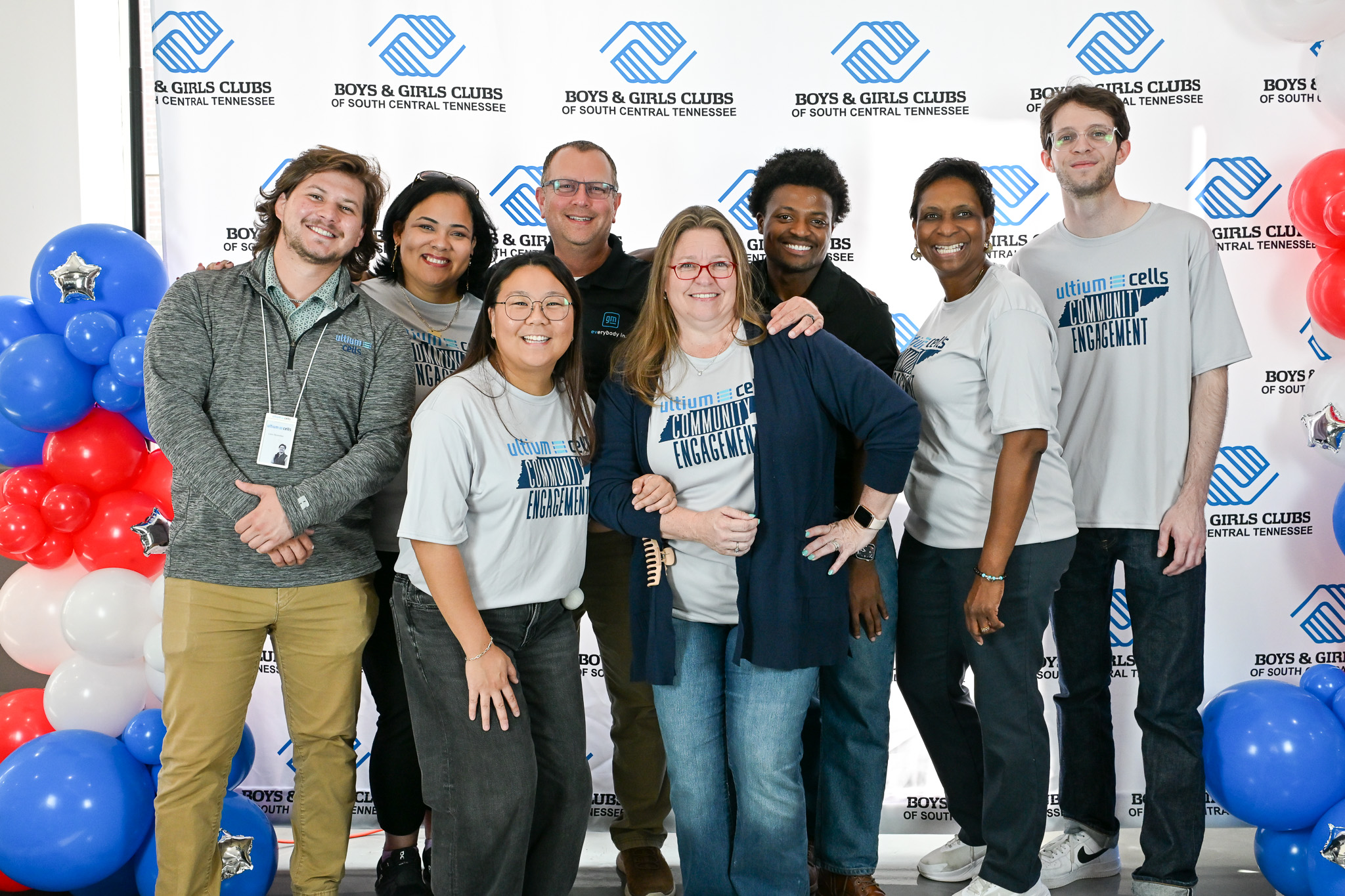Eight Ultium Cells volunteers pose for a group photo in front of a Hero of the Year backdrop in Spring Hill.
