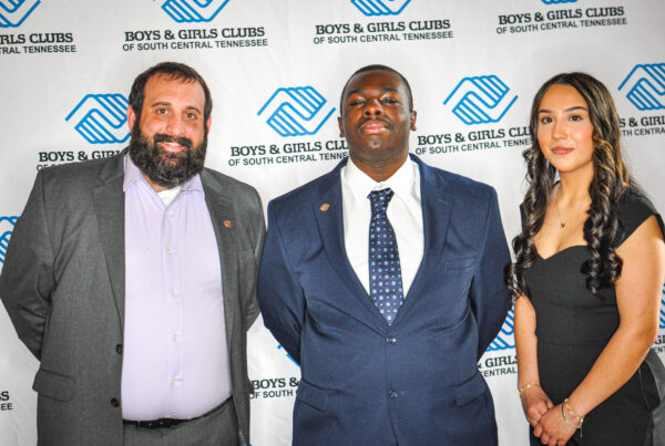 Three professionally dressed individuals posing at a Boys & Girls Clubs event.