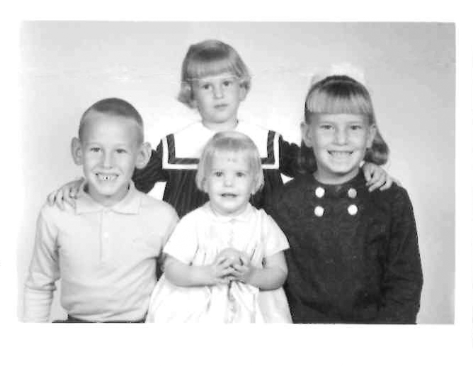 Black and white photo of four children posing together.