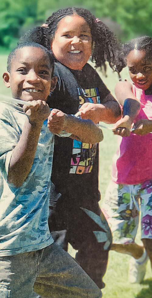 Children playing tug-of-war outdoors on a sunny day.